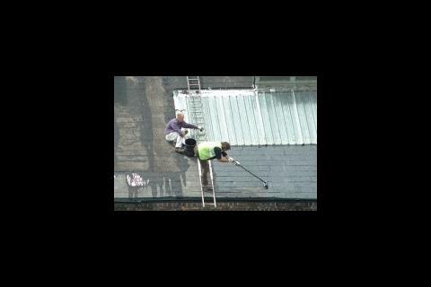 Man leaning on broom on roof